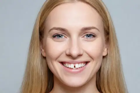 Uśmiechnięta blondynka z wyraźną szparą między zębami, która jest widoczna nawet przy krótkim wędzidełku.
